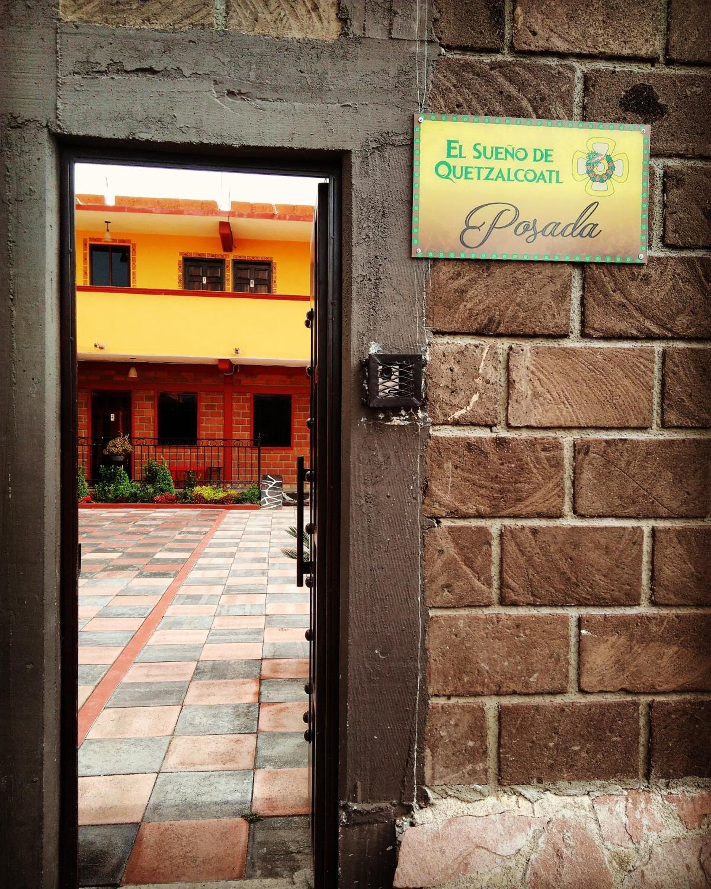 Entrada de um prédio com uma placa indicando "El Sueno de Quetzalcoatl Posada".
