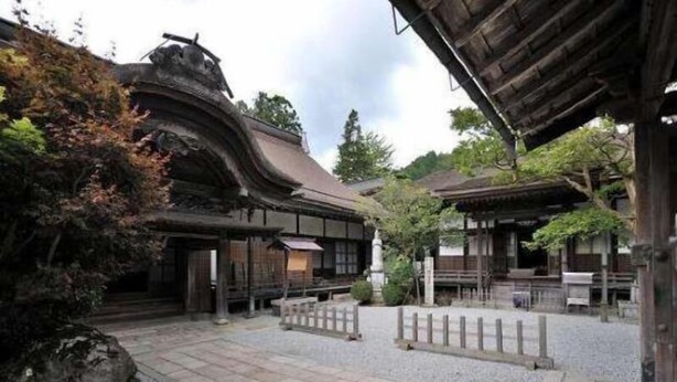 A traditional Japanese courtyard with wooden buildings, stone pathways, and a small pond. - Daienin (Koya)