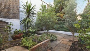 A garden with various plants and a brick wall. - Belgravia Apartments - Cathcart Road (London)
