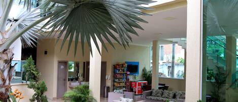 Amplio espacio interior con una palmera grande, asientos, televisor y un bar de aperitivos.