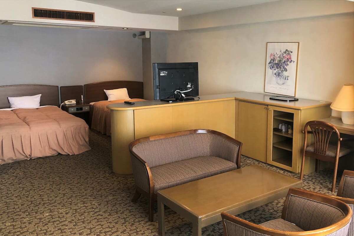 Une chambre d’hôtel avec deux lits, un bureau, une télévision, une chaise et une lampe.