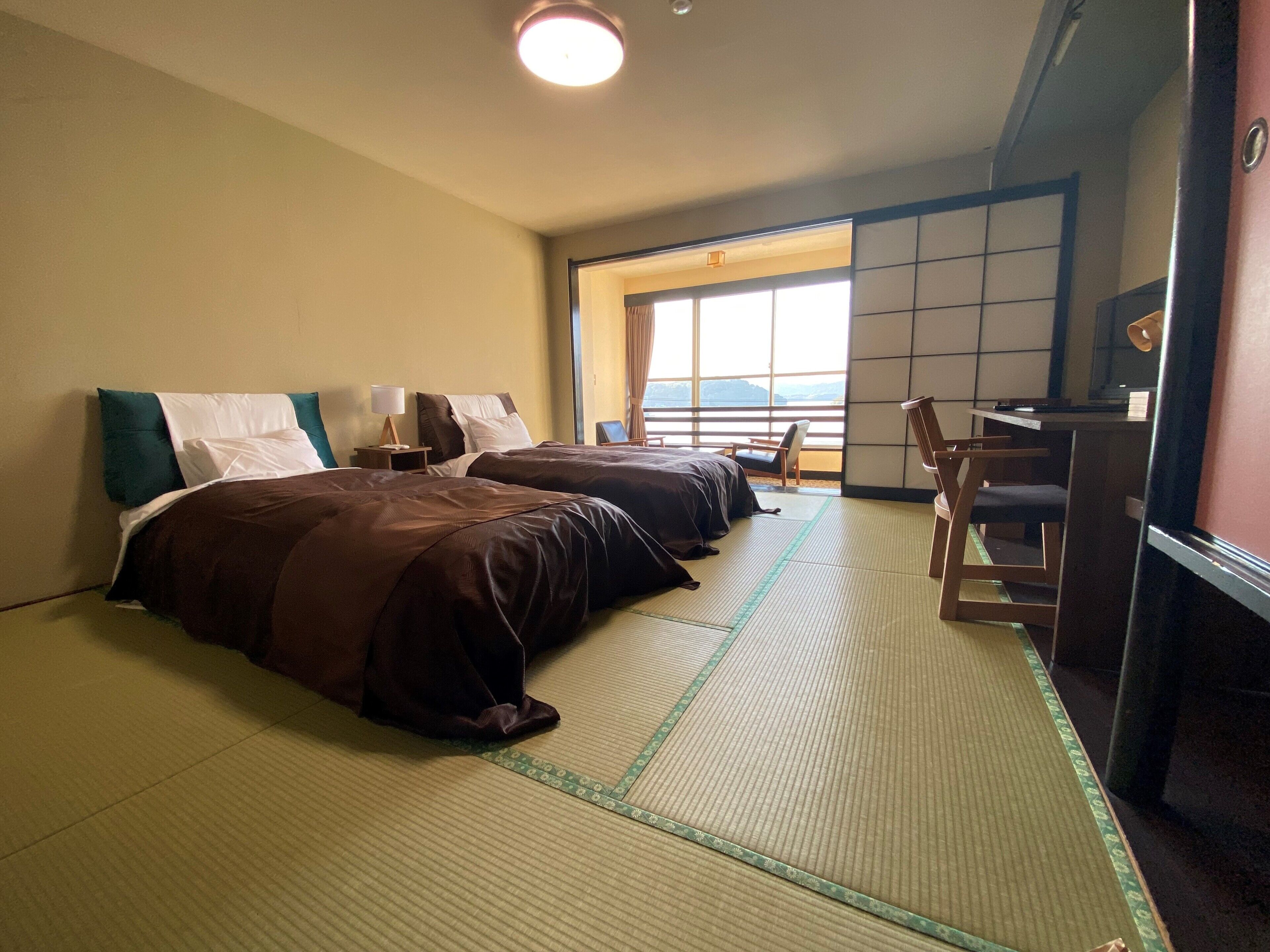 Une chambre d’hôtel avec deux lits, un bureau et vue sur la mer.