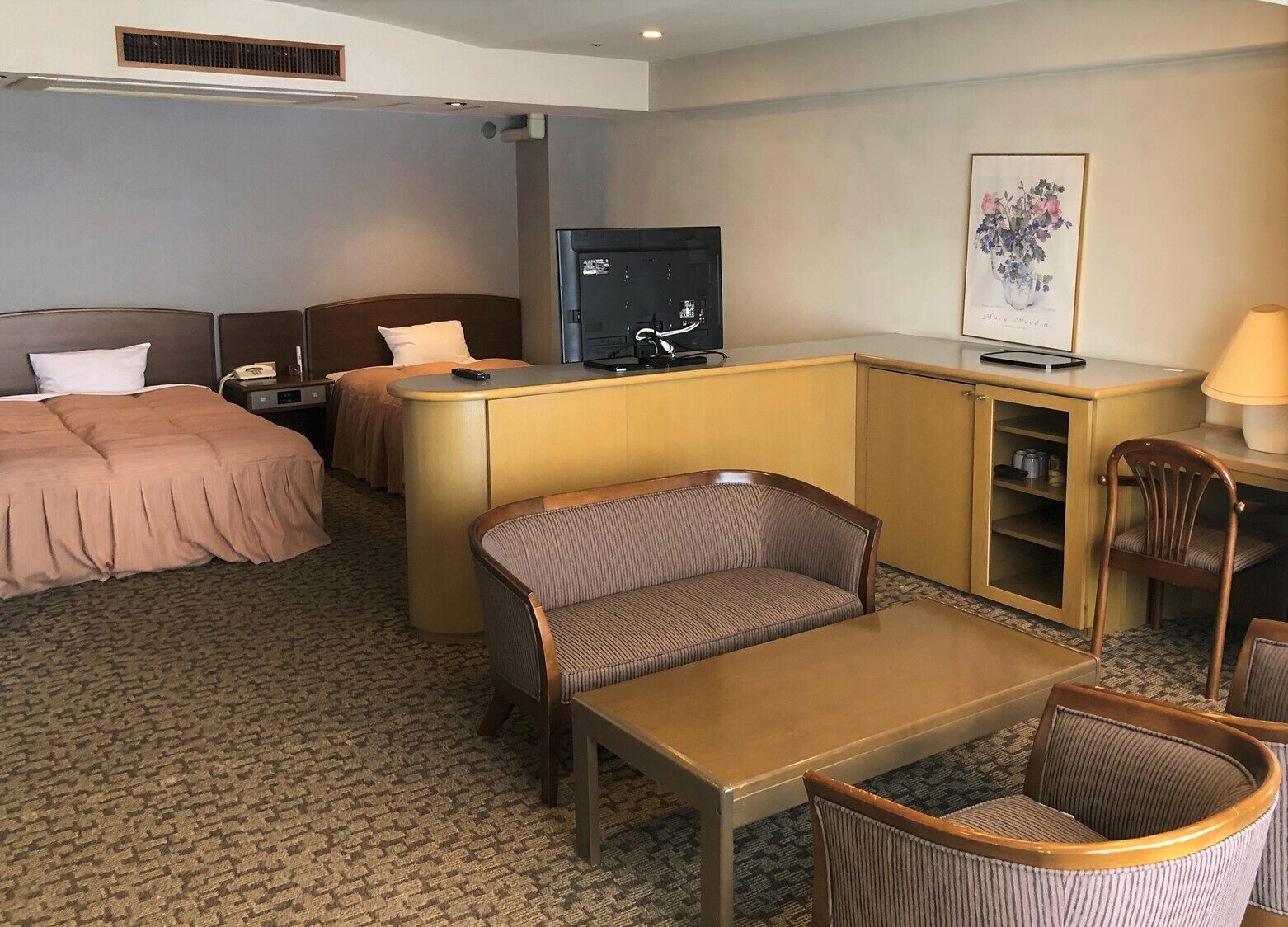 Une chambre d’hôtel comprenant un lit, un bureau, une télévision, une chaise et un canapé.