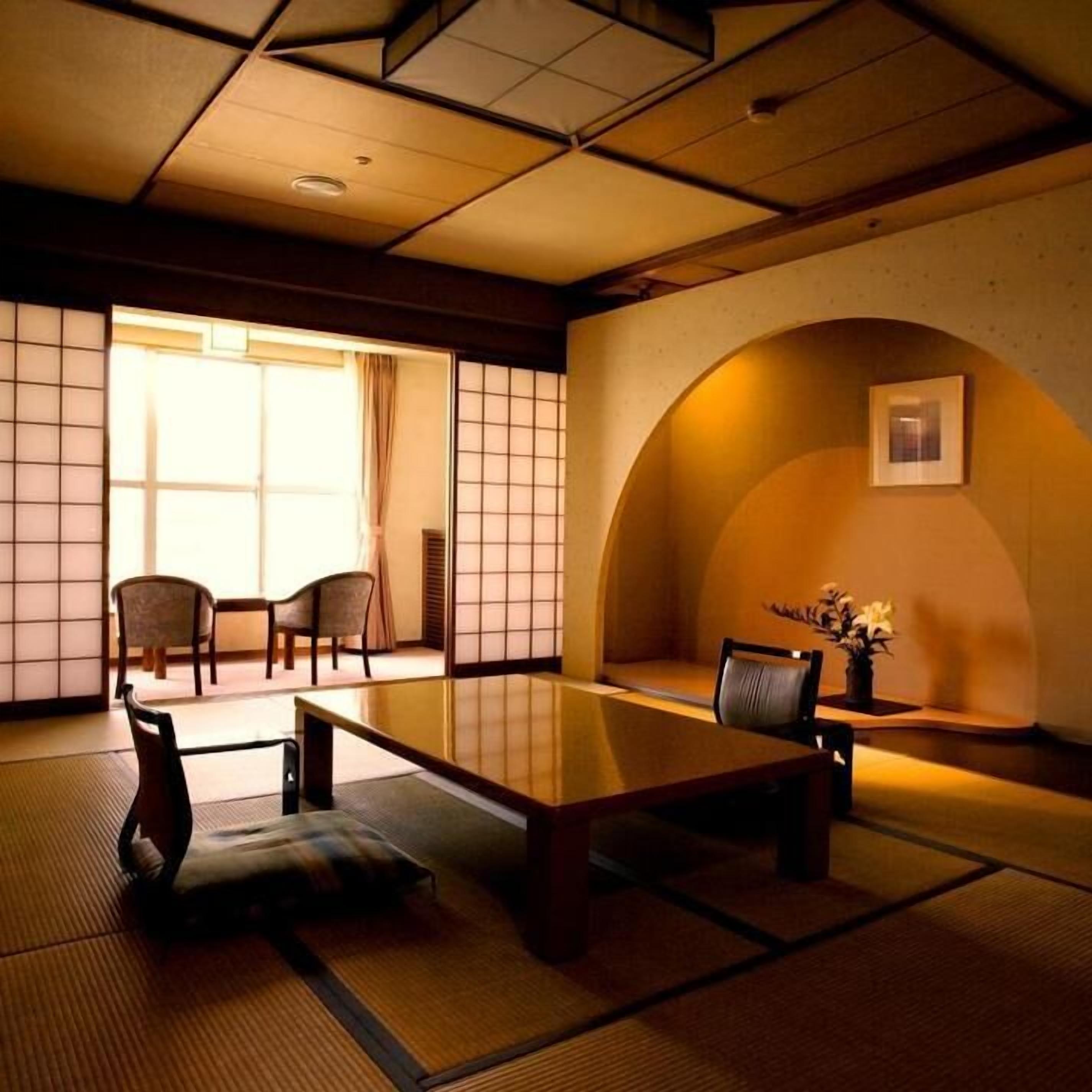 Une pièce de style japonais traditionnel, avec un sol recouvert de tatamis, une table basse et des chaises.