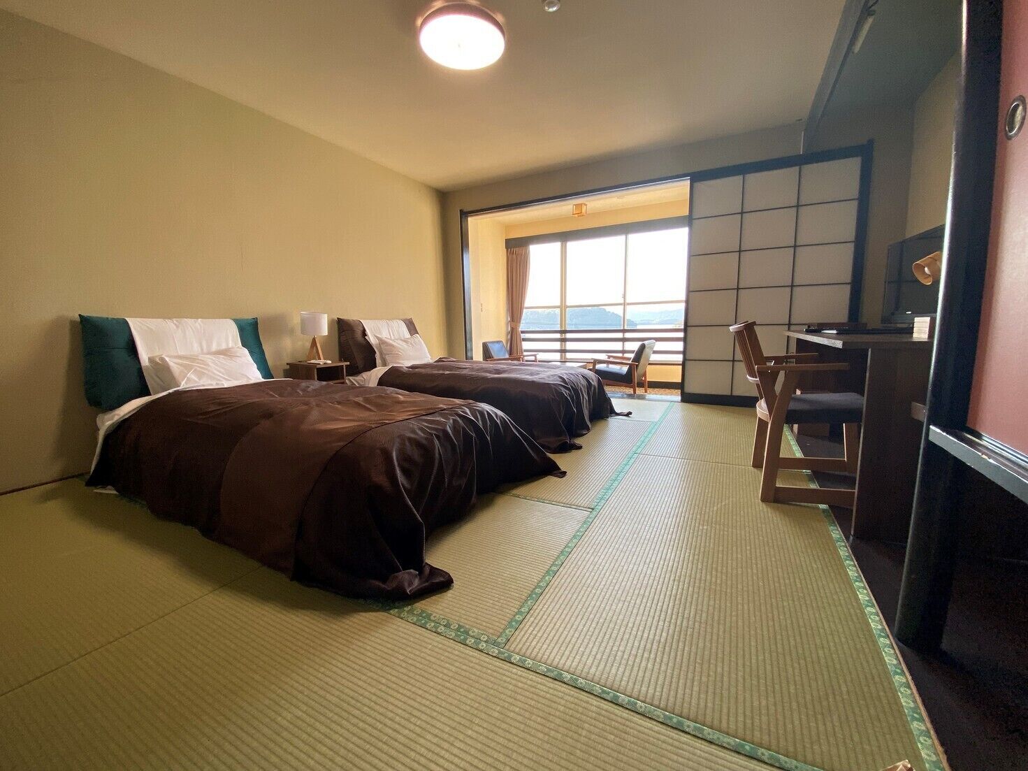 Une chambre d’hôtel avec deux lits, un bureau et une vue sur l’extérieur.