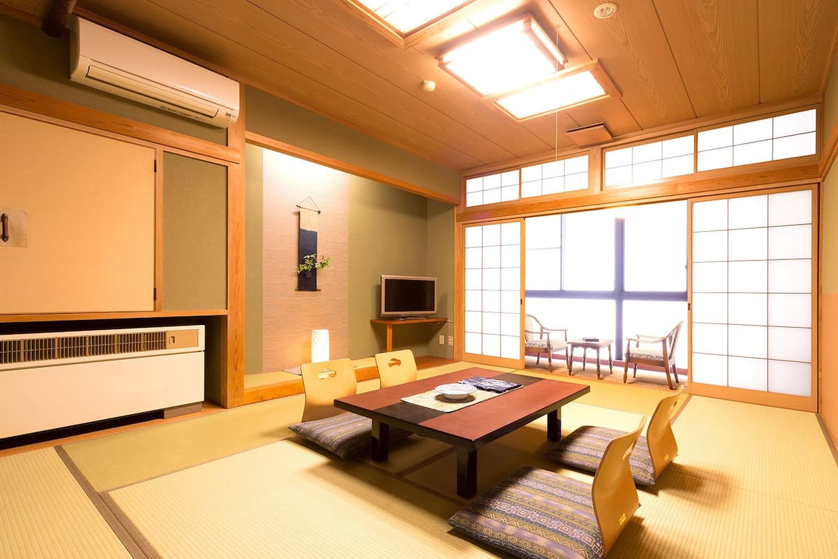 Ein traditioneller japanischer Raum mit Tatami-Böden, einem niedrigen Tisch und verschiebbaren Türen.