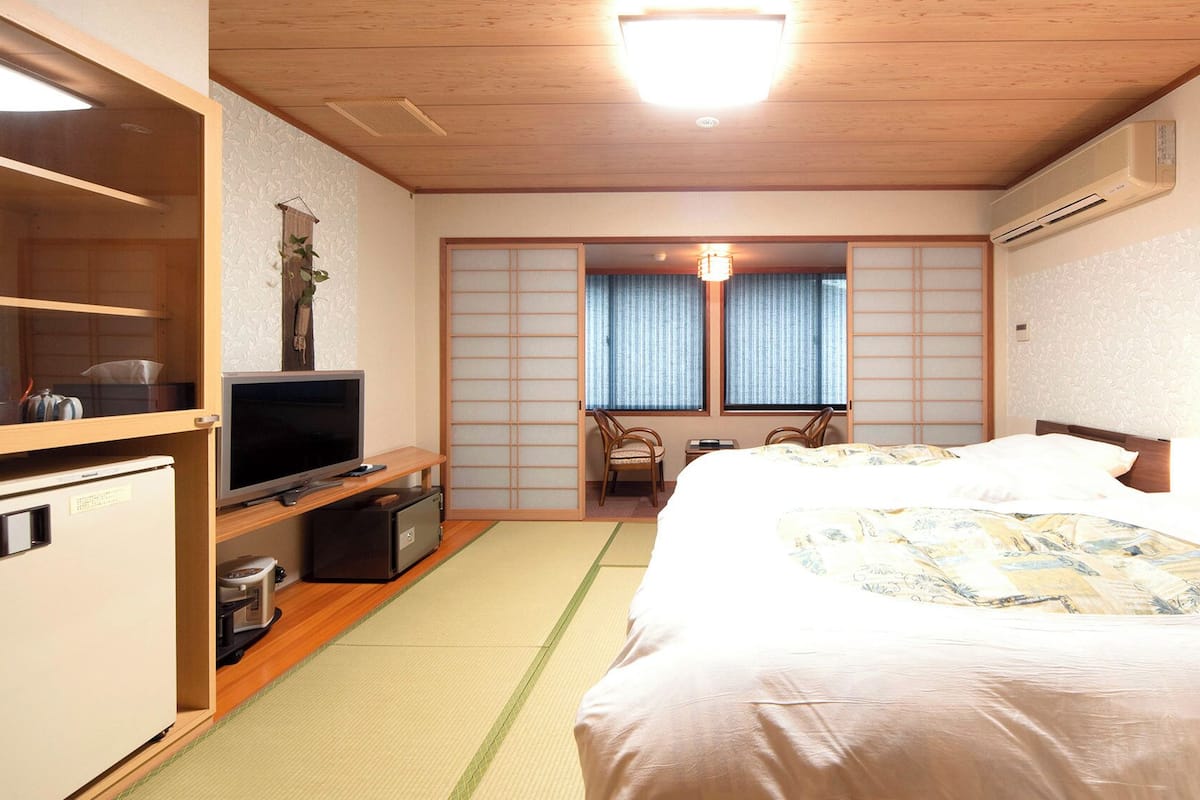 Ein Hotelzimmer mit Bett, Fernseher, Schreibtisch und Kleiderschrank.