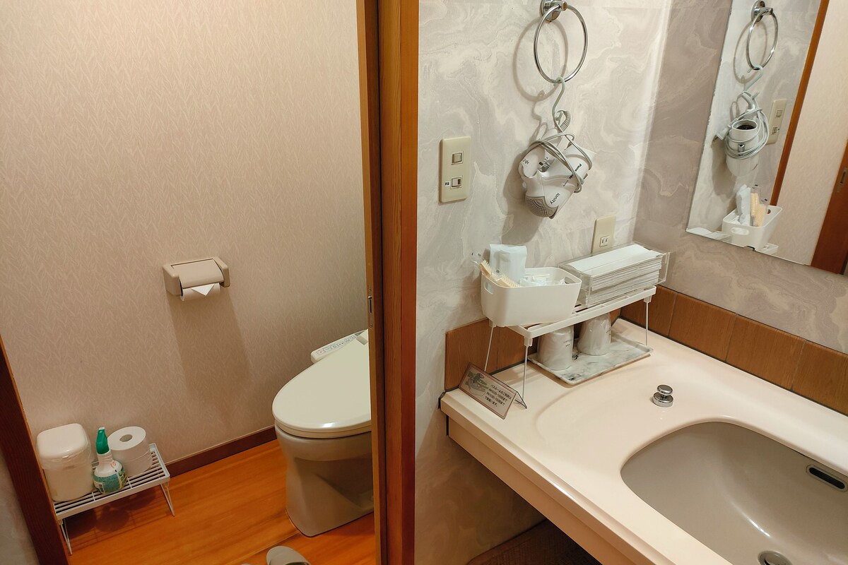 A bathroom with a toilet, sink, and shower area.