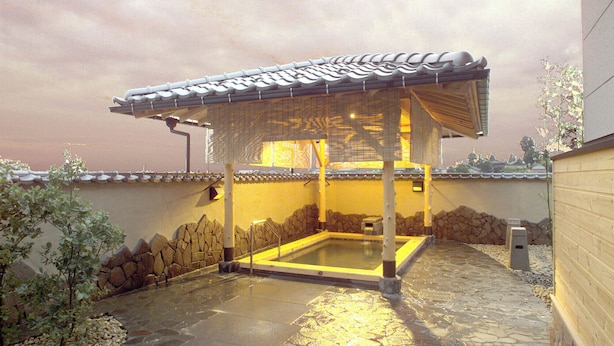 A traditional Japanese onsen with a stone bath, tiled roof, and wooden walls. - Yunomiko Onsen (Kamiichi)