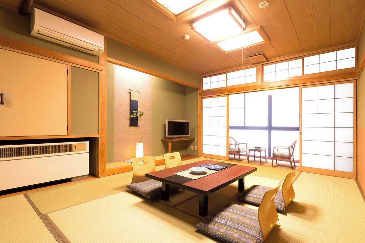 Une pièce de style japonais traditionnel, avec un sol recouvert de tatamis, une table basse et des portes coulissantes.