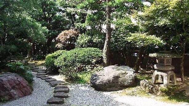 A garden with a gravel path, rocks, and a stone lantern. - Hotel Yoshihara (Toyama)