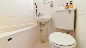 A bathroom with a bathtub, sink, toilet, and a showerhead. - Hotel Shoen (Toyama)