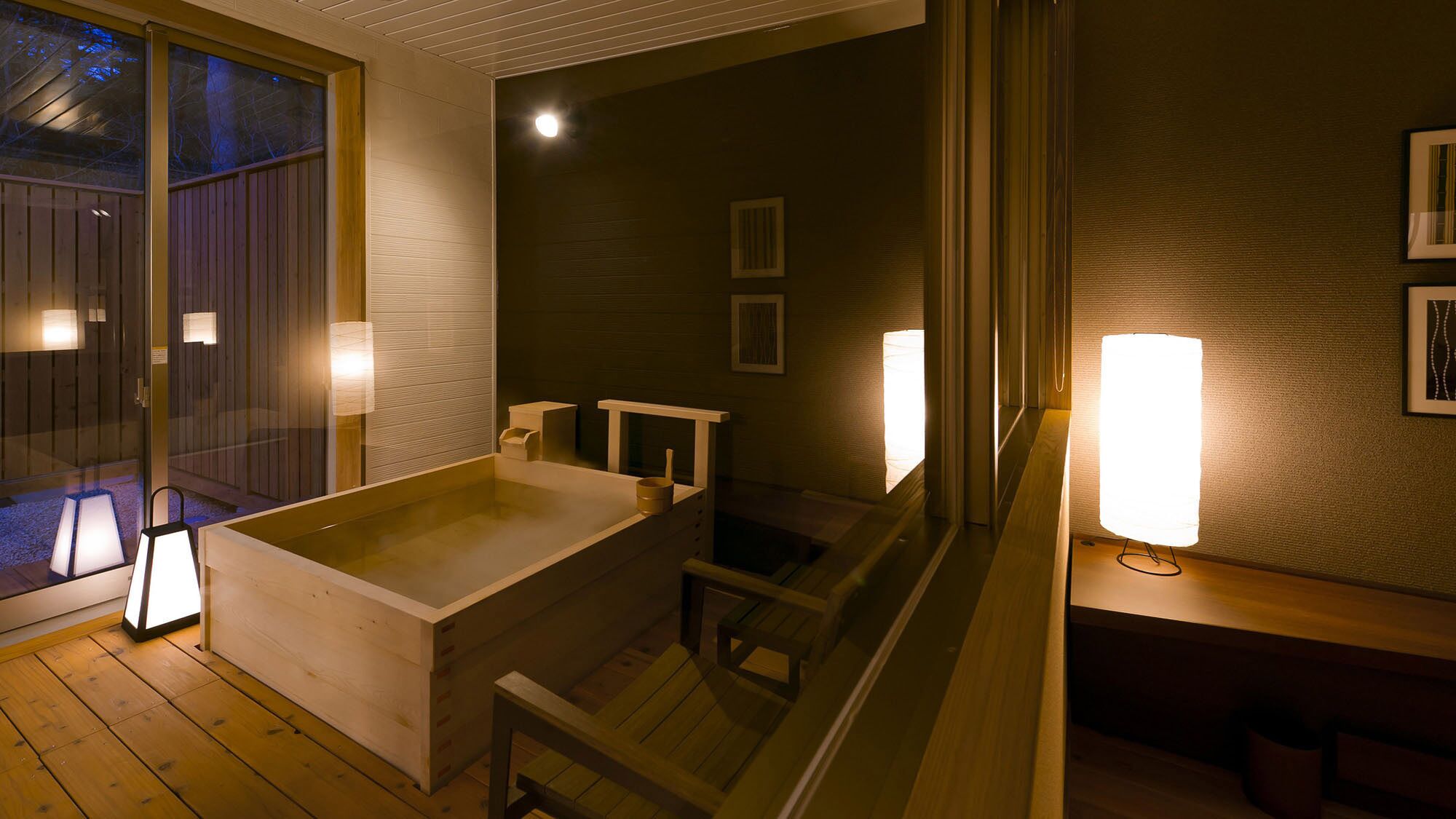 Ein Zimmer mit einer grossen Badewanne, Holzboden und Wandleuchten.