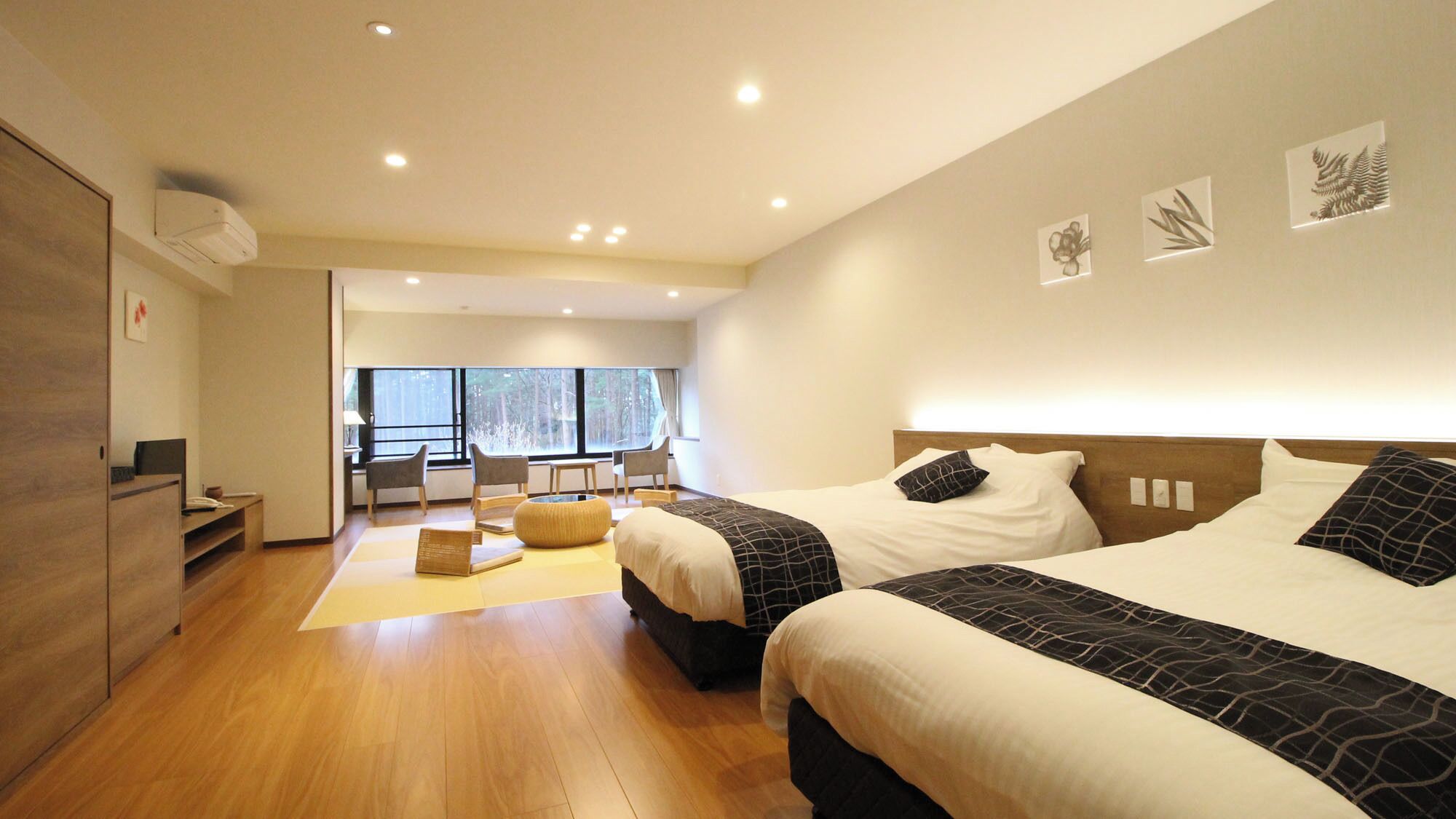 Ein modernes Hotelzimmer mit zwei Betten, einer Sitzecke und großen Fenstern.