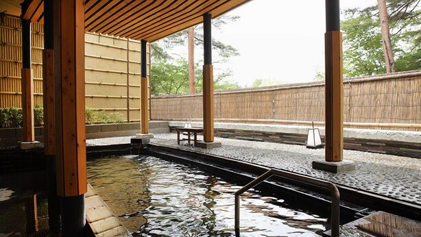 A traditional Japanese onsen with a wooden structure, stone steps, and a bamboo wall. - Hotel Fuuka (Hokuto)