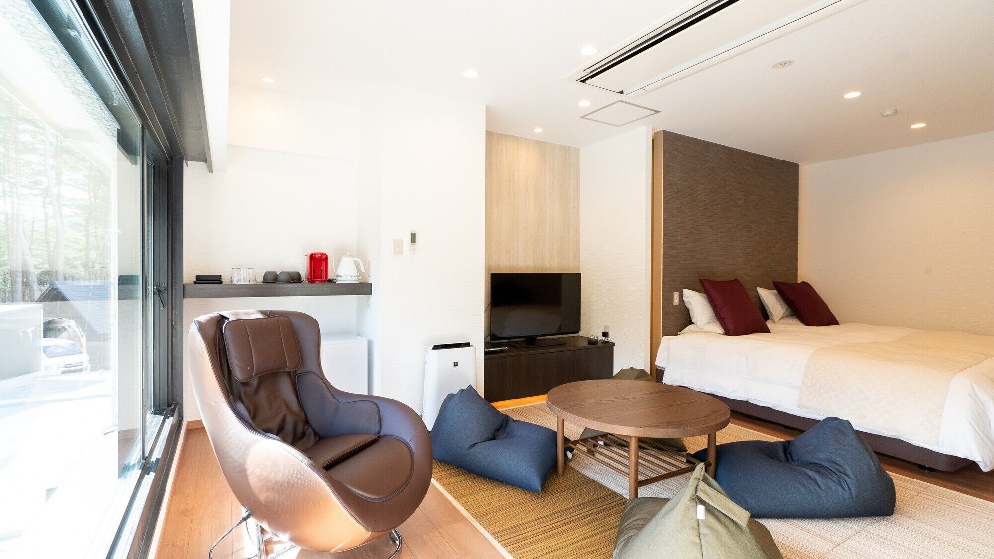 Ein modernes Hotelzimmer mit Sofa, Bett, Fernseher und einem kleinen Tisch.