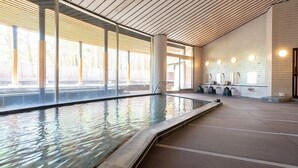 A swimming pool with a tiled interior, large windows, and a tiled wall with a grid pattern. - Hotel Fuuka (Hokuto)