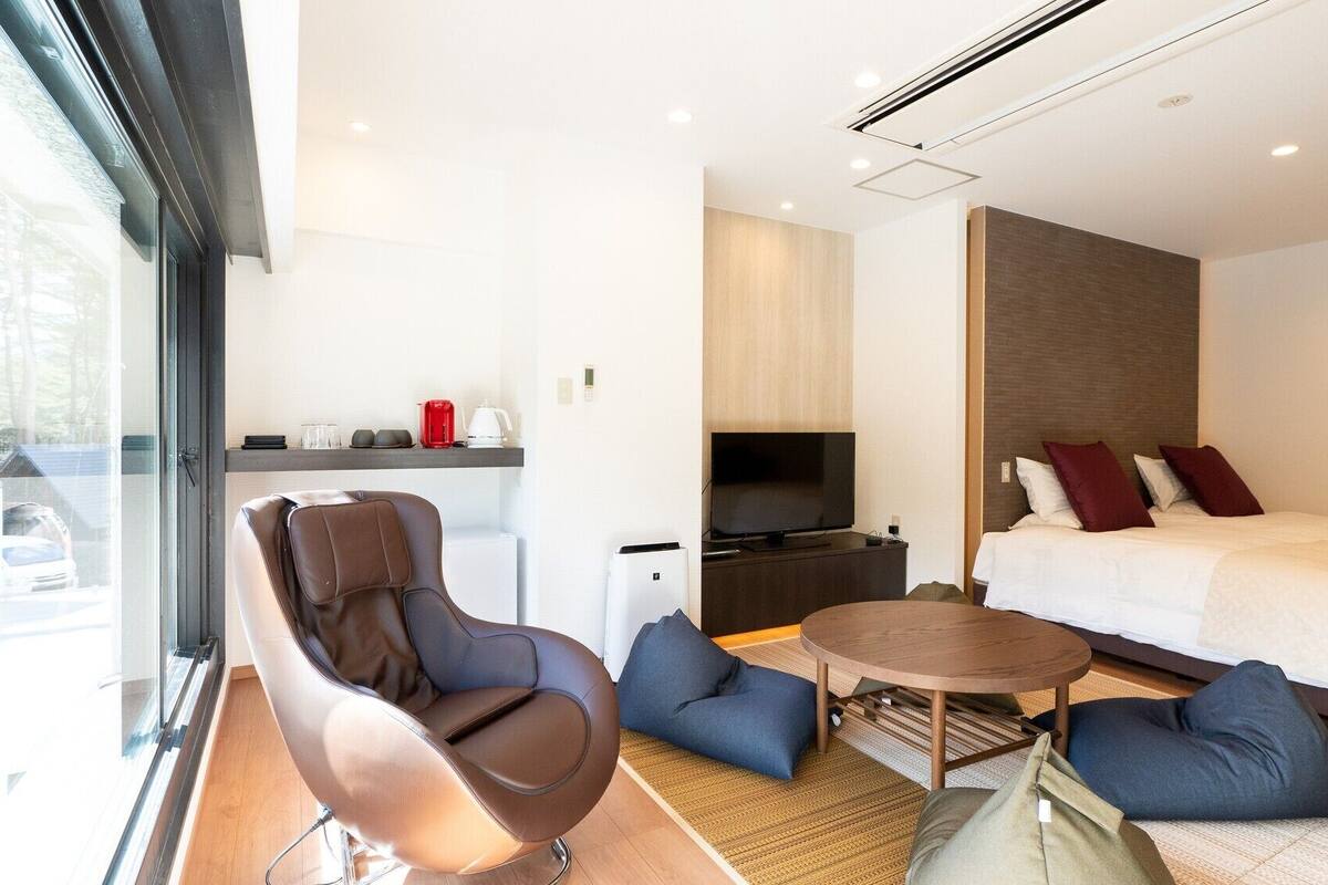 Ein modernes Hotelzimmer mit Bett, Fernseher, Sofa und Couchtisch.