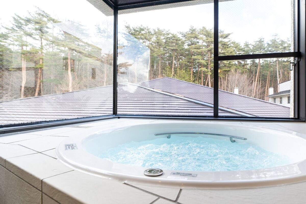 Ein Whirlpool mit freiem Blick auf einen Wald durch große Fenster.