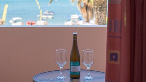 A table with a bottle and two glasses, overlooking a beach with palm trees and boats. - Alkyon Beach Hotel (Corfu)