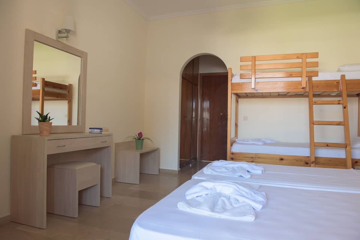 A bedroom with a bunk bed, a desk with a mirror, and a small seating area.
