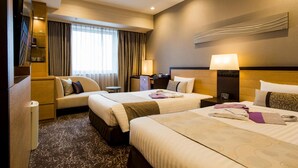 Une chambre d’hôtel avec deux lits, un canapé, un bureau et une fenêtre avec des rideaux.