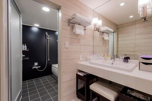Et moderne badeværelse med bruser, toilet og en vaskebord med vask og spejl.