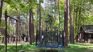 Un área boscosa con un trampolín, cabañas de madera y un cartel de prohibido fumar.