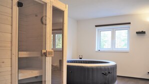 Una habitación con una cama inflable grande y circular, una puerta de madera y una ventana con vistas a árboles.