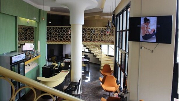 A modern interior with a central column, seating area, and a TV screen. - Douala Design Hotel (Douala)