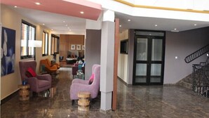 A spacious lobby with a high ceiling, a staircase, and seating areas. - Douala Design Hotel (Douala)