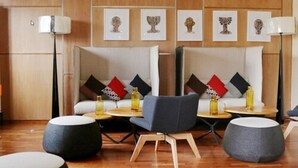 A modern lounge area with two sofas, a small table, and two ottomans. - Douala Design Hotel (Douala)