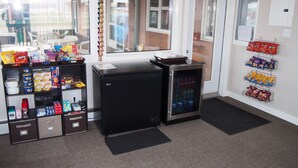 Een snackbar met een koelkast, vriezer en drankkoeler, gevuld met diverse snacks en drankjes.