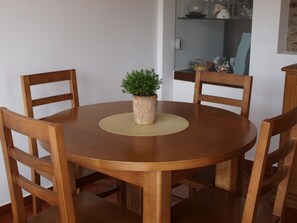 A round wooden dining table with four chairs, a woven placemat, and a potted plant in the center. - Casa da Fraga (Macedo de Cavaleiros)