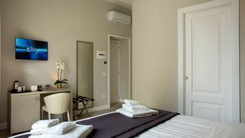 Una camera d'albergo con un letto, una scrivania, una sedia, una televisione e una porta.