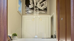 Un corridoio con una reception in legno bianca con la scritta 'Naplesuite', una porta in legno e un'opera d'arte appesa al muro.