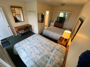 A compact room with two beds, a desk, a television, and a mirror. - Wasaga Beach Inn And Cottages (Wasaga Beach)