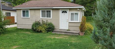 A single-story house with a front door, two windows, and a small porch.