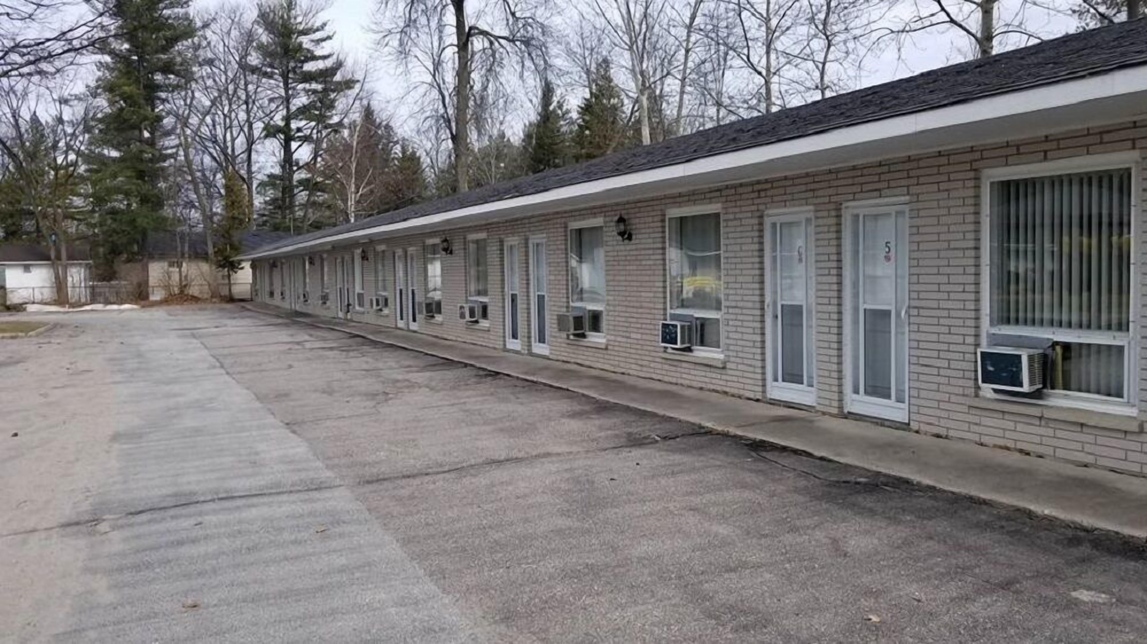 A motel with a row of rooms, each with a window and an air conditioning unit.