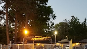Ein Schwimmbad mit Liegestühlen und einer überdachten Sitzgelegenheit.