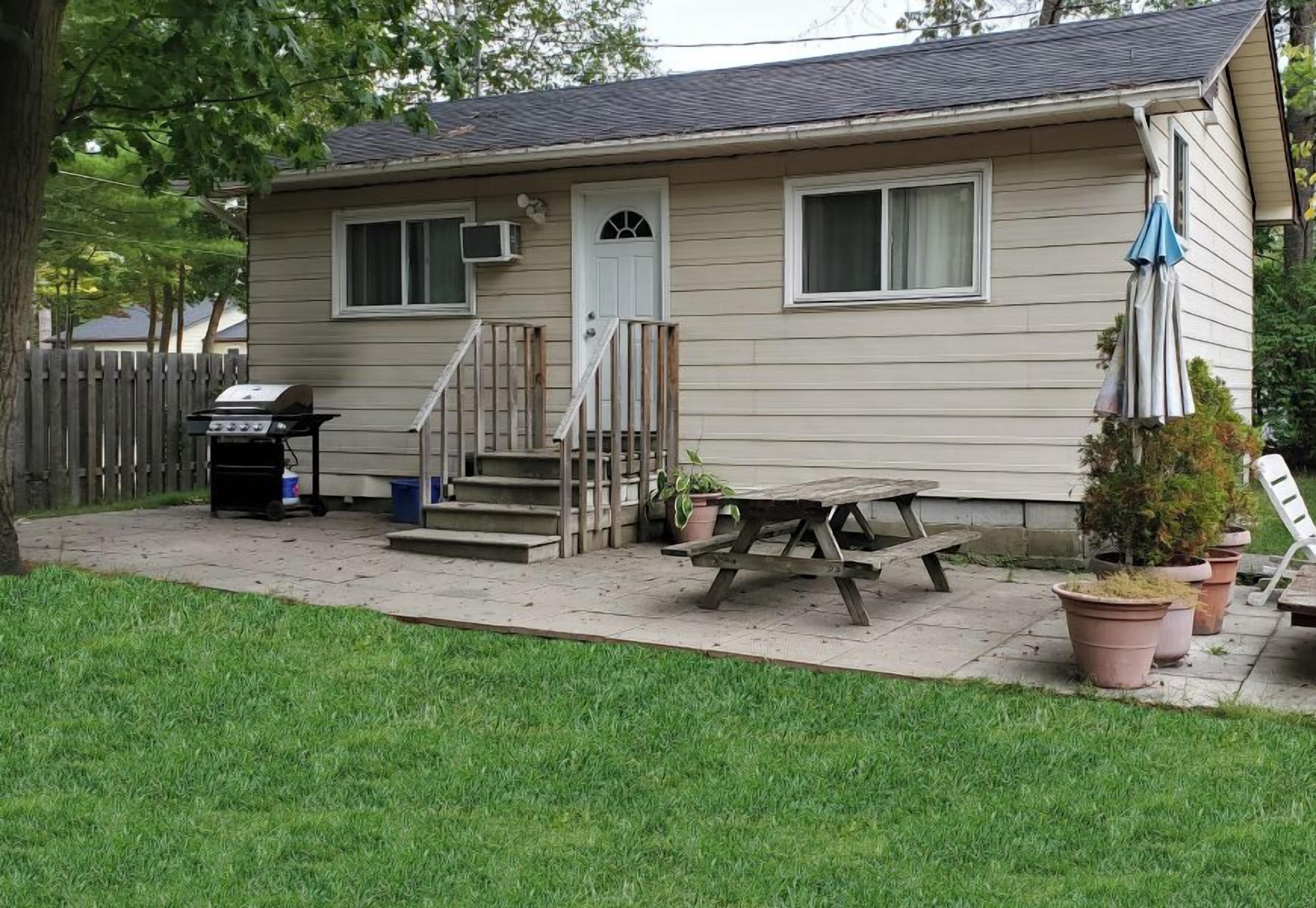 Ein Bungalow mit Veranda, Grill und Picknicktisch.