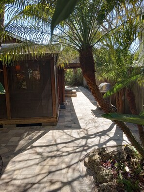 Relax under a shaded pergola surrounded by lush greenery and a majestic palm tree.