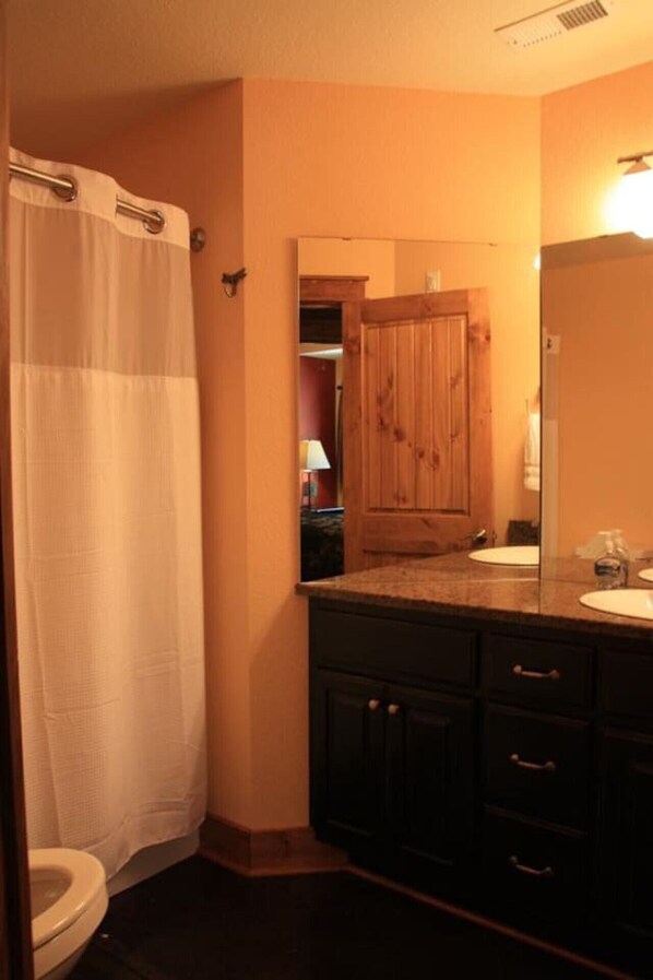 Un baño con cortina de ducha, armarios de madera, lavabo y espejo.