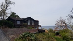 A log cabin with a deck overlooking a body of water.