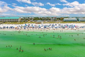 A beach with numerous umbrellas and people enjoying the water. - Ocean Kiss'D | Private Pool | 6-Seater Golf Cart | 3 Min Walk to Beach (Destin)