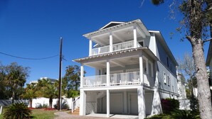 Une maison à deux étages avec un balcon à l’étage supérieur, un porche couvert à l’avant et une allée menant à l’entrée.