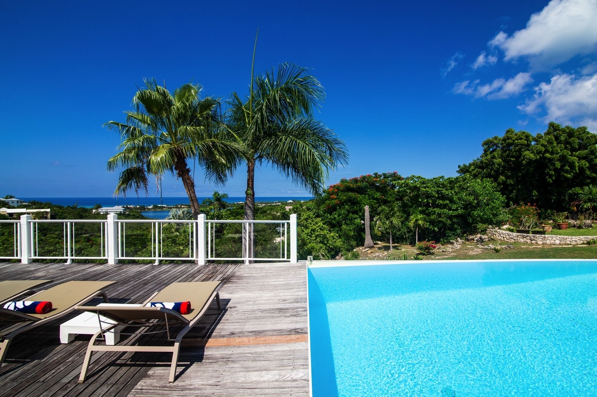 A wooden deck with lounge chairs and a swimming pool.