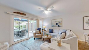 A living room with a sofa, armchair, coffee table, and a dining area with chairs and a table. - The Pool Is At Your Doorstep! (Hilton Head)