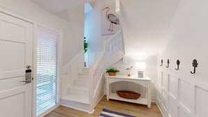 A white staircase with a landing table, a basket, and wall-mounted hooks. - The Pool Is At Your Doorstep! (Hilton Head)
