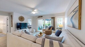 A living room with a sofa, armchairs, a coffee table, a TV, and a ceiling fan. - The Pool Is At Your Doorstep! (Hilton Head)